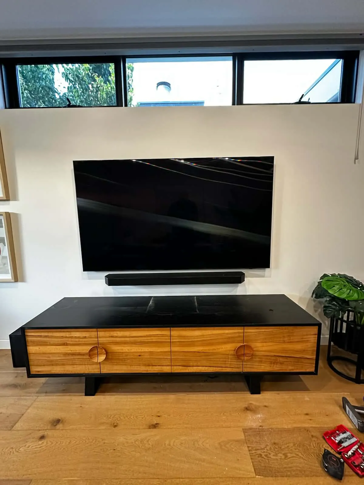 Big screen TV mounted above floating timber entertainment unit